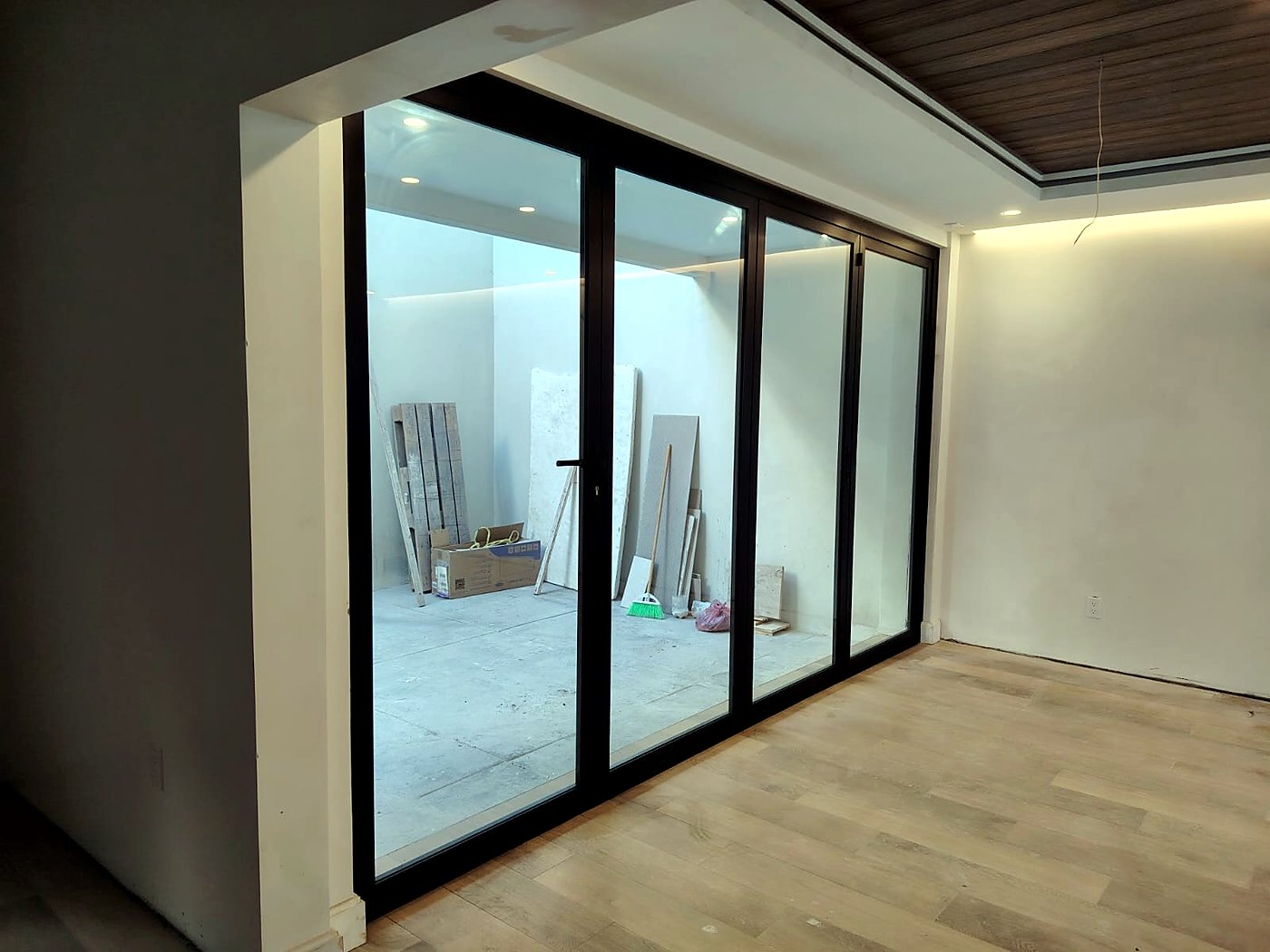 Puerta plegable de aluminio y vidrio instalada por Vidriera ROVIC en una sala con vista al patio